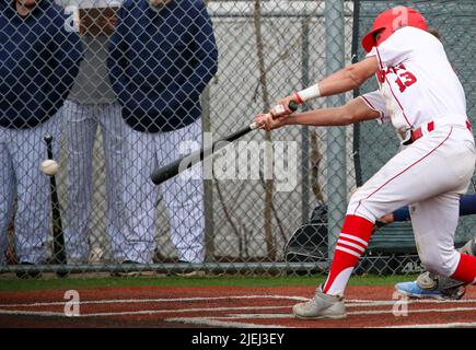 Un joueur de baseball d'école secondaire se balance à la balle qui lui a été pendu pendant un match. Banque D'Images