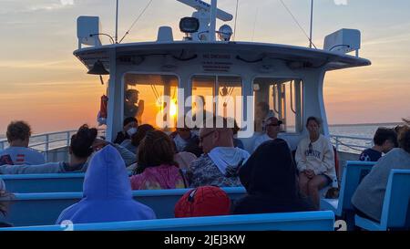 Bay Shore, New York, États-Unis - 30 mai 2022 : passagers sur un ferry de Fire Island, regardant le coucher du soleil à travers les fenêtres du pont des capitaines o Banque D'Images