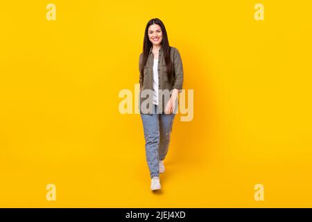 Photo pleine longueur de gaie belle femme mûre marcher le week-end sourire isolé sur fond de couleur jaune Banque D'Images