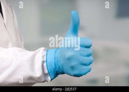 Le gros plan des mains dans les gants médicaux montre les pouces vers le haut Banque D'Images