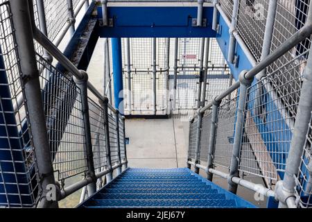 vue sur le paysage vue sur un ensemble d'escaliers extérieurs en métal, des poteaux de guidage et des mains courantes, avec des marches de pont bleues Banque D'Images