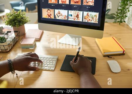 Gros plan de retouche à l'aide d'une tablette graphique pour retoucher des photos sur un écran d'ordinateur à un tableau Banque D'Images