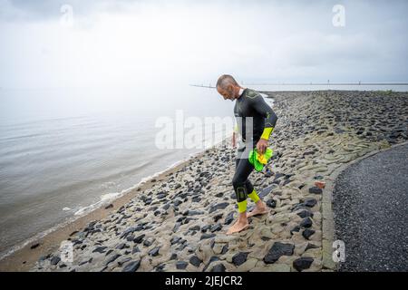 Greetsiel, Allemagne. 27th juin 2022. Frank Feldhus entre dans la mer du Nord à la baie de Ley, en combinaison avec la frison oriental. Il nage vers sept îles et revient en sept jours. L'Oldenburger veut attirer l'attention sur la pollution des mers avec son action. Il nagez de la baie à Borkum. Les jours suivants, il nagera de Juist, Norderney, Baltrum, Langeoog, Spiekeroog et Wangerooge vers le continent. Au total, il couvrira 66 kilomètres. Credit: Mohssen Assanimoghaddam/dpa/Alay Live News Banque D'Images