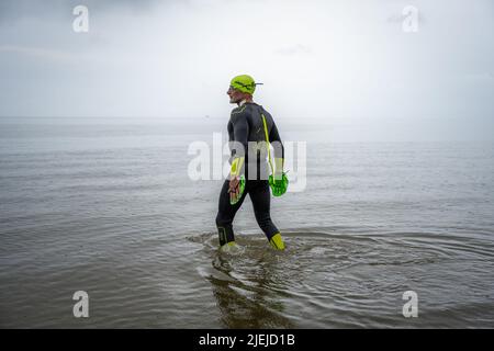 Greetsiel, Allemagne. 27th juin 2022. Frank Feldhus se trouve dans sa combinaison en mer du Nord, dans la baie de Ley, en frison oriental. Il nage vers sept îles et revient en sept jours. L'Oldenburger veut attirer l'attention sur la pollution des mers avec son action. Il nagez de la baie à Borkum. Les jours suivants, il nagera de Juist, Norderney, Baltrum, Langeoog, Spiekeroog et Wangerooge vers le continent. Au total, il couvrira 66 kilomètres. Credit: Mohssen Assanimoghaddam/dpa/Alay Live News Banque D'Images