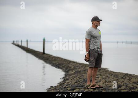 Greetsiel, Allemagne. 27th juin 2022. Frank Feldhus est sur le point de commencer sa baignade dans la baie de Ley, en frison oriental, et regarde autour de lui. Il nagé dans sept îles et de retour dans sept jours. L'Oldenburger veut attirer l'attention sur la pollution des mers avec son action. Il nagez de la baie à Borkum. Les jours suivants, il nagera de Juist, Norderney, Baltrum, Langeoog, Spiekeroog et Wangerooge vers le continent. Au total, il couvrira 66 kilomètres. Credit: Mohssen Assanimoghaddam/dpa/Alay Live News Banque D'Images