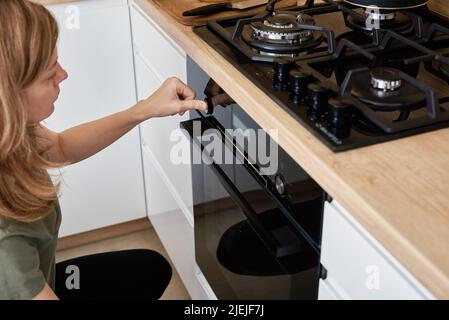 Main féminine Choisissez le programme de cuisson sur le bandeau de commande du four électrique, femme utilisant le four électrique, appareils ménagers modernes Banque D'Images