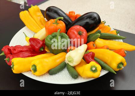 Assiette blanche de légumes avec poivrons, poivre jaune, aubergine sur une table noire Banque D'Images