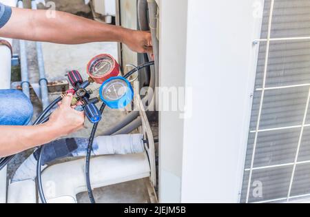 Mécanicien de réparation de l'air utilisant des équipements de mesure pour remplir les climatiseurs industriels d'usine. Banque D'Images