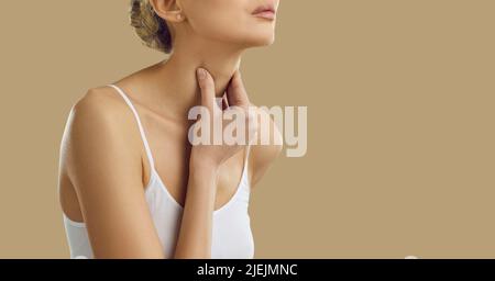 Femme souffrant de mal de gorge, de difficulté à avaler et de perte de voix sur fond beige. Banque D'Images