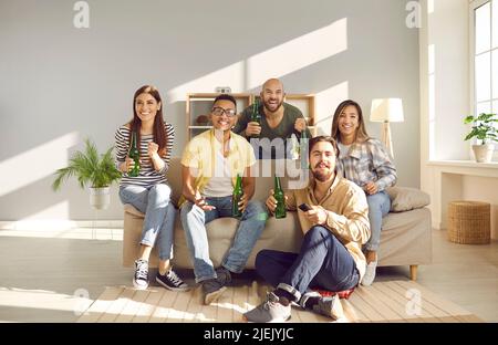 Des amis multiraciaux, hommes et femmes, regardent des compétitions sportives à la télévision à la maison. Banque D'Images