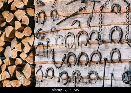 mur en bois avec de vieux fers à cheval rouillés et du bois de chauffage Banque D'Images