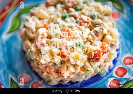 Salade traditionnelle ukrainienne ou russe appelée olivie olivier macro gros plan texture avec des pommes de terre hachées, des carottes, des petits pois et des oignons au mayonnais Banque D'Images