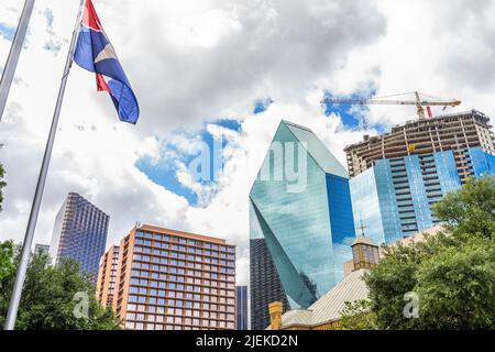 Dallas, Texas, vue panoramique du centre-ville, vue à angle bas, bâtiments modernes, grue de construction et drapeau sur poteau dans un ciel nuageux Banque D'Images