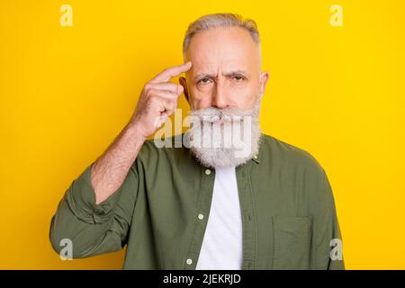 Photo portrait de l'homme âgé a eu mauvaise humeur en gardant le doigt près du front isolé couleur jaune vif fond Banque D'Images