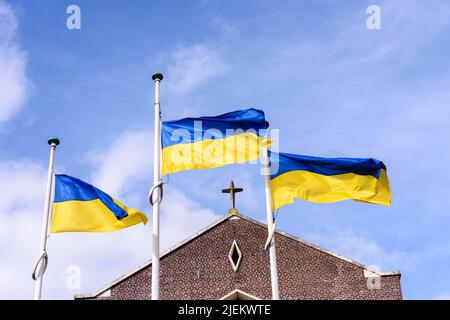 Trois drapeaux ukrainiens volent sur les mâts à l'extérieur de l'église Saint-Pierre et Saint-Paul, Portlaoise, comté de Laois, République d'Irlande. Banque D'Images