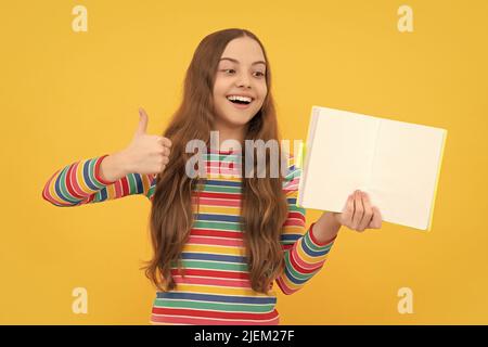 Entièrement satisfait de la scolarité. Bonne fille donner les pouces vers le haut tenant le livre ouvert. Faites vos études Banque D'Images