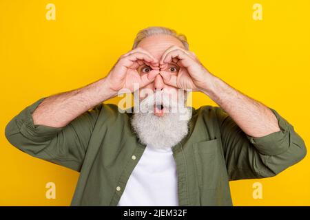 Photo portrait de grand-père regardant loin dans binoculaire isolé couleur jaune vif fond Banque D'Images