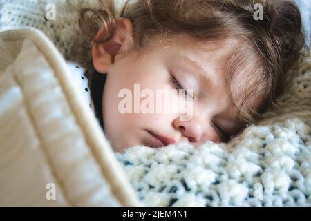 Gros plan d'une petite fille dormant paisiblement enveloppée dans une couverture chaude Banque D'Images