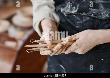 Mains de jeunes femmes créatives artisanales tenant un tas d'outils à main en bois pour sculpter des motifs ornementaux sur des objets en argile Banque D'Images