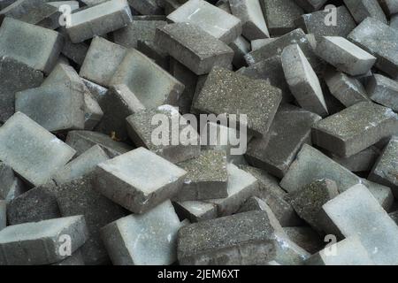 Pile de briques de béton gris fond de briques de construction humides qui se trouvent sur le chantier de construction. Pile de briques de pavés en granit gris prêtes à être posées Banque D'Images