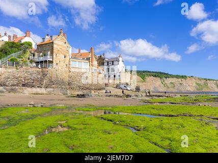Robin Hood Bay Yorkshire avec la plage de sable du Bay Hotel et les rochers recouverts d'algues avec le village de Robin Hood Bay Yorkshire Angleterre GB Banque D'Images