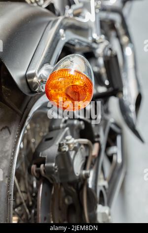 Un clignotant orange, un signal et un indicateur sur une moto noire brillante. Gros plan texture détaillée de l'ampoule d'avertissement utilisée pour la sécurité routière, précaution Banque D'Images