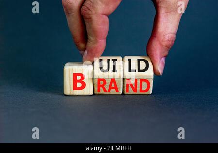 Créez votre symbole de marque. Concept mots construire la marque sur des cubes en bois. Main d'homme d'affaires. Magnifique fond gris de table. Créez votre marque et votre bussin Banque D'Images