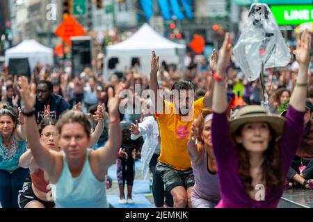 Tim Tompkins, en chemise jaune, de l'Alliance Times Square à Times Square à New Yorkpratiquant le yoga au solstice d'été, premier jour de l'été, mardi, 21 juin 2022. Le Solstice 20th annuel de Times Square, « Mind Over Madness », parrainé par Peloton, le Consulat général de l'Inde, New York et Smartwater, entre autres, étend la capacité du yogis à bloquer le bruit et l'image de fond qui les entourent à la croisée des chemins du monde. Le premier jour de l'été a été déclaré Journée internationale du yoga par les Nations Unies. (© Richard B. Levine) Banque D'Images