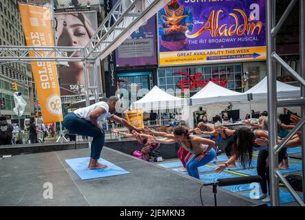 L'instructeur de yoga Douglass Stewart instruit un étudiant à Times Square à New York sur le solstice d'été, premier jour de l'été, mardi, 21 juin 2022. Le Solstice 20th annuel de Times Square, « Mind Over Madness », parrainé par Peloton, le Consulat général de l'Inde, New York et Smartwater, entre autres, étend la capacité du yogis à bloquer le bruit et l'image de fond qui les entourent à la croisée des chemins du monde. Le premier jour de l'été a été déclaré Journée internationale du yoga par les Nations Unies. (© Richard B. Levine) Banque D'Images