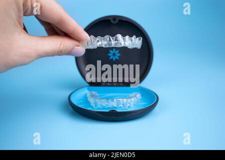 Femme tenant les dispositifs de retenue transparents invisalign avec une boîte sur la table, plan de dessus. Mise au point sélective Banque D'Images