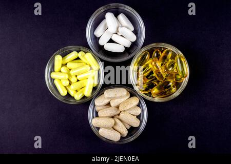 Quatre différents types de suppléments de sport à base de plantes en capsules et en vitamine médecine vue de dessus sur fond noir Banque D'Images