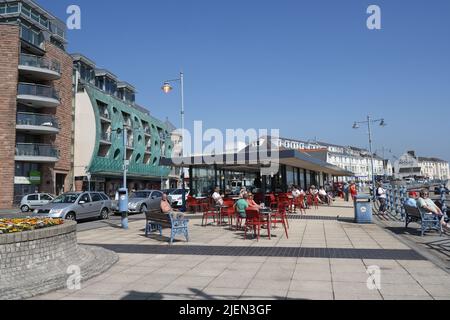 La promenade du front de mer à Porthcawl au pays de Galles Royaume-Uni, station balnéaire galloise. Les gens assis à côté du café de rue de la côte du pays de Galles staycation Banque D'Images