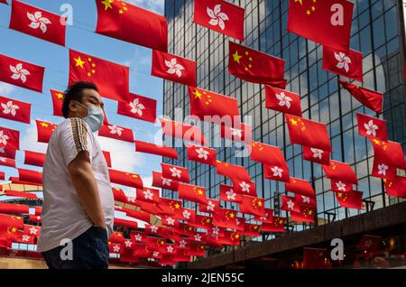 Hong Kong, Chine. 27th juin 2022. Un piéton attend de traverser la rue tandis que les drapeaux de la République populaire de Chine et de la RAS de Hong Kong sont exposés avant le 1 juillet anniversaire de la remise de Hong Kong à la Chine à Hong Kong. (Photo par Miguel Candela/SOPA Images/Sipa USA) crédit: SIPA USA/Alay Live News Banque D'Images