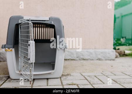 Boîte vide avec porte ouverte pour transporter les chats sur fond de mur Banque D'Images