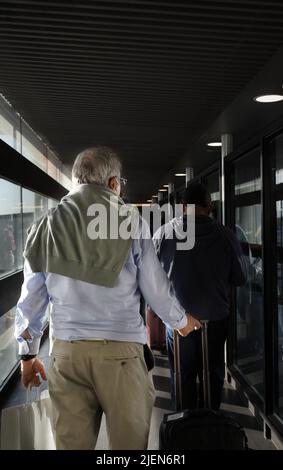 Un homme plus âgé qui embarque dans l'avion à travers la porte Banque D'Images