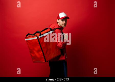 Livraison par messagerie avec sac à dos rouge livraison des commandes de produits alimentaires. Homme livrant des repas rapides avec sac à dos thermique. Service de livraison de nourriture. Banque D'Images