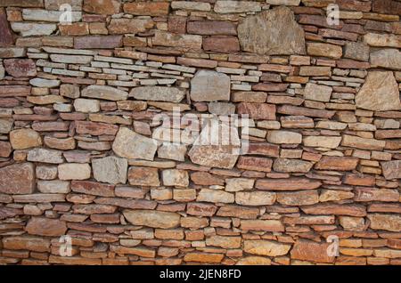 Un mur de pierre différent est fait de pierres de différentes tailles. Mur en pierre asymétrique. Banque D'Images