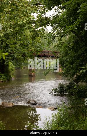 Le vieux pont en bois se dresse au-dessus de la rivière qui coule doucement Banque D'Images