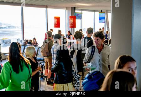 Schiphol, pays-Bas. 26th juin 2022. Les voyageurs attendent dans les couloirs de départ pour prendre leur vol depuis l'aéroport de Schiphol. L'aéroport avertit maintenant sans équivoque qu'il pourrait y avoir des heures de files d'attente dans les semaines à venir. Au cours de la période à venir, il sera aussi occupé que pendant les vacances de mai. KLM met un frein à la vente de billets pour les vols qui partiront de Schiphol dans les jours à venir. Crédit : SOPA Images Limited/Alamy Live News Banque D'Images