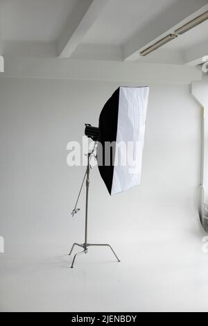 Flash photo professionnel avec une grande softbox sur un pied en C sur un cyclorama dans un studio photo moderne avec de grandes fenêtres. Éclairage professionnel Banque D'Images