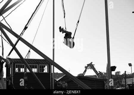 fille sautant dans un parc d'attractions en boucle et s'amusant. photographie en noir et blanc. Tramore, Irlande Banque D'Images