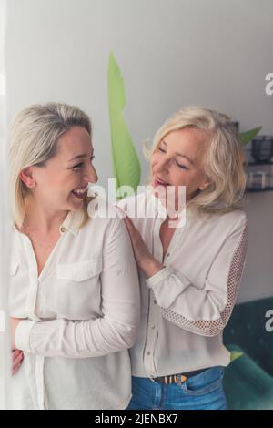 Photo verticale moyenne en intérieur de femmes caucasiennes à la mode, debout et se tenant ensemble et se tenant les uns les autres et souriant. Photo de haute qualité Banque D'Images