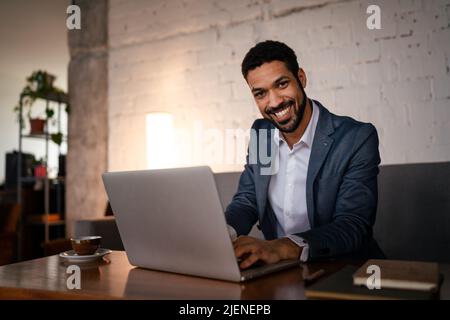 Un jeune homme d'affaires heureux ayant un café et faisant son travail dans un café. Banque D'Images