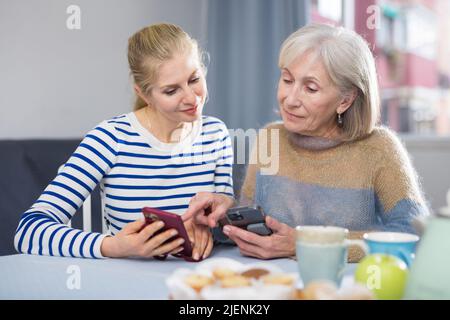 Femme adulte avec sa fille adulte regardant des photos sur un téléphone portable Banque D'Images