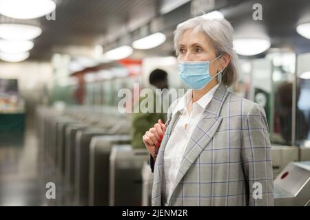 Femme âgée dans un masque à l'entrée de la station de métro Banque D'Images