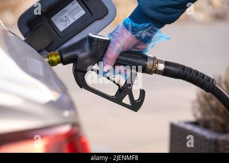 Diesel.Prix du carburant en Europe. Ravitaillement de la voiture.pistolet de ravitaillement dans les mains d'un homme dans un gant bleu.voiture à une station-service. Voiture argent, ravitaillement Banque D'Images