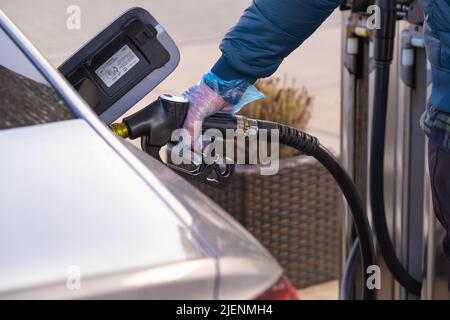 Diesel.Prix du carburant en Europe. Ravitaillement de la voiture.pistolet de ravitaillement dans les mains d'un homme dans un gant bleu.voiture à une station-service. Voiture argent, ravitaillement Banque D'Images
