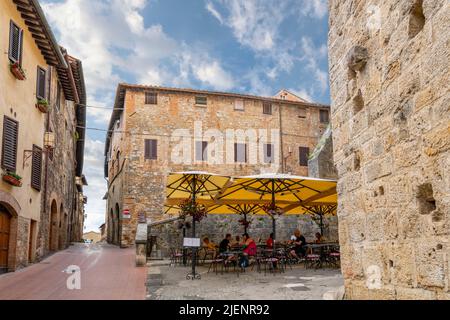 Un petit café-terrasse situé à l'intérieur des murs de la ville médiévale de San Gimignano, en Italie, dans la région toscane. Banque D'Images
