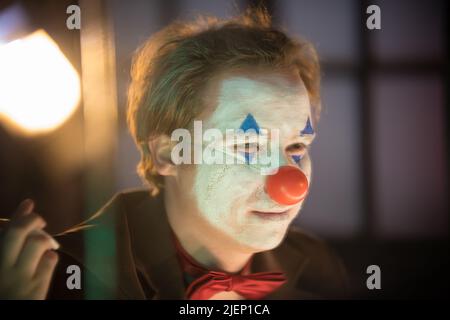 Clown concept - un homme avec le visage peint regardant dans le miroir Banque D'Images