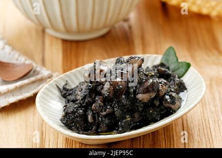 Sélection de Squid frit et de Chili Focus Stir dans une sauce à l'encre noire Squid servie dans une assiette en céramique. Connu sous le nom de Tumi Cumi Hitam Pedas en Indonésie. Banque D'Images